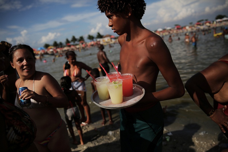 A boy sells caipirinhas, a Brazilian cocktail, at an artificial pond known as piscinao, or big pool, in the northern suburbs of Rio de Janeiro January 8, 2017.