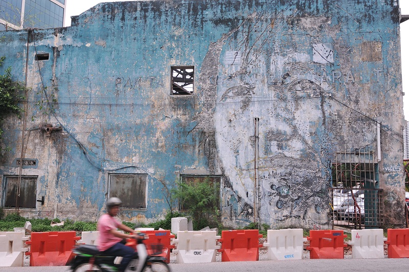 A portrait of a woman drilled into the side of a vacant building by Vhils.