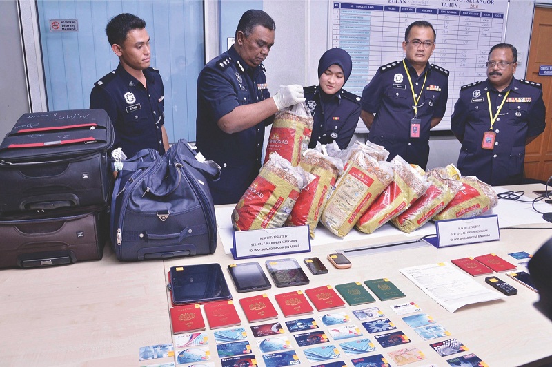 Abdul Aziz (second left) and investigating officer Inspector Mardiah Mohamed (centre) remove the substances from the plastic bags packed in the suitcases. u00e2u20acu201d Picture by Kwong Wah Yit Poh