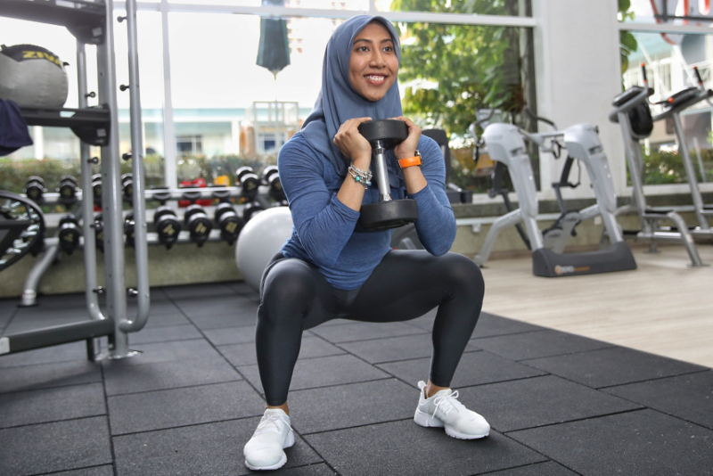 Ain demonstrating how she does squats with a 12kg dumbbell.