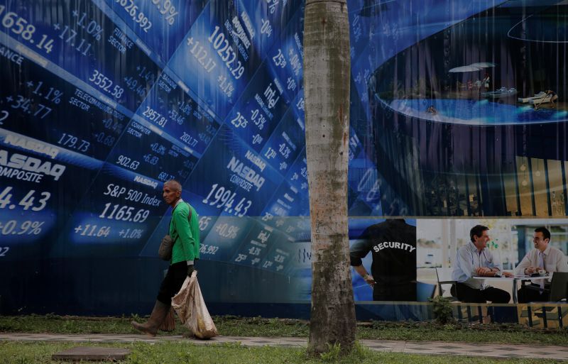 A worker walks in front of a stock market poster at Sudirman Business District compound in Jakarta February 2, 2017. u00e2u20acu2022 Reuters pic