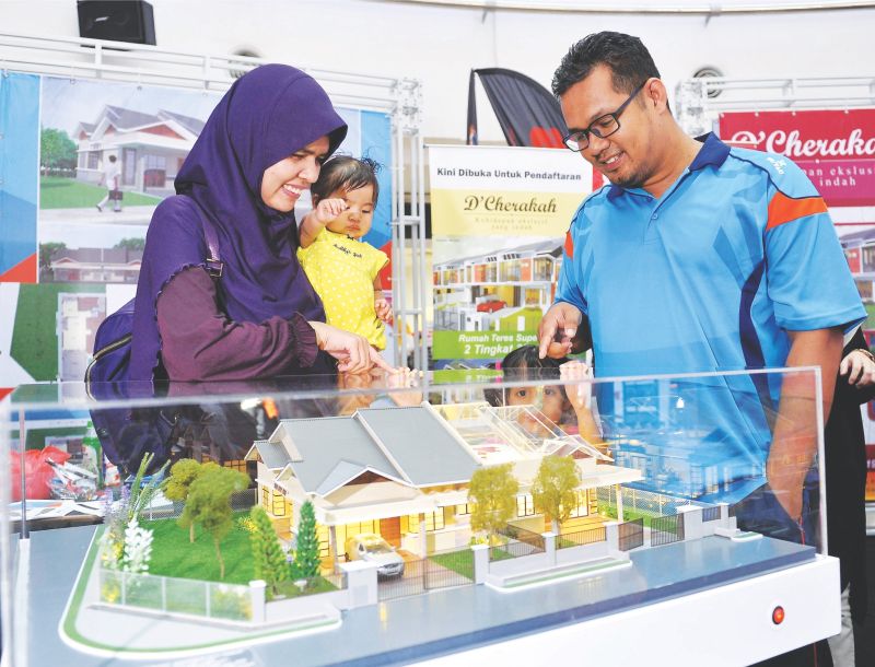 Mohamad Razik Mohamad Taib (right) and his wife Farah Mohd Saaf were seen viewing a model of a house at the exhibition on Sunday. — Bernama pic