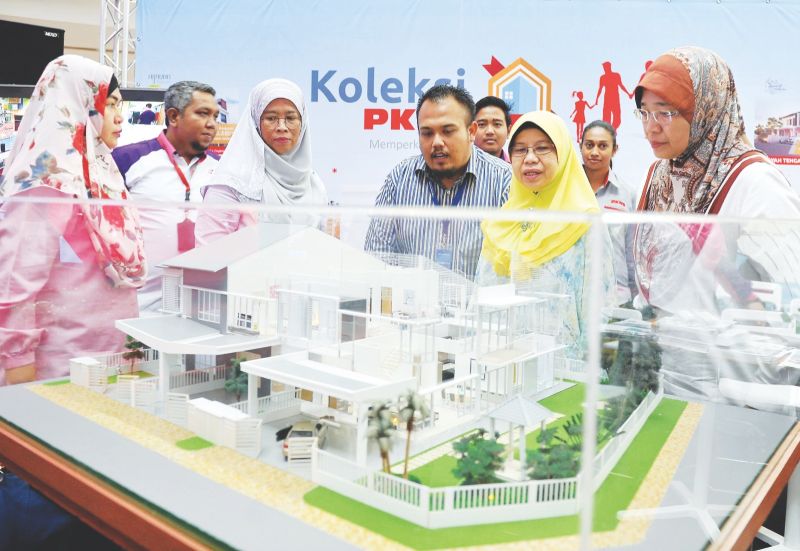 Noraida (in yellow headscarf) was seen viewing a double-storey semi-detached home model availble for first time home buyers. — Bernama pic
