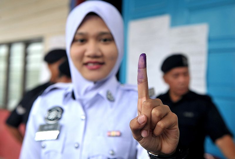 Traffic police constable Noor Aliah Abu Talib, 24, showing her ink-stained finger after casting a vote at a community hall in Kampung Sungai Lundu, February 12, 2017, in early voting for the Tanjong Datu by-election. u00e2u20acu201d Bernama pic