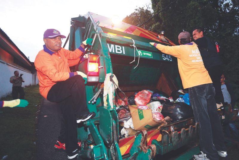 Datuk Seri Zambry Abd Kadir (left) rides on a garbage truck on his day as a council worker. u00e2u20acu201d Picture by Farhan Najib