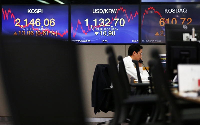 A currency dealer works in front of electronic boards showing the Korea Composite Stock Price Index (KOSPI) (left) and the exchange rate between the South Korean won and the US dollar at a bank in Seoul March 22, 2017. u00e2u20acu201d Reuters pic