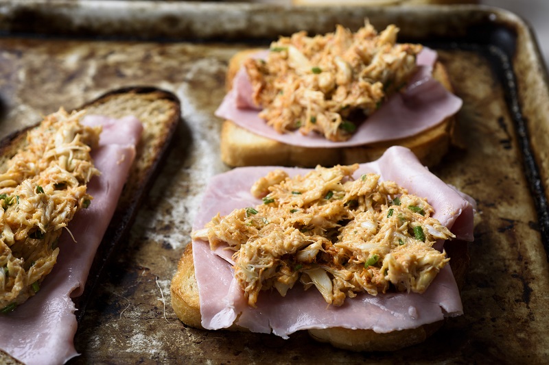The crab meat spread atop thin-sliced ham and slices of bread, ready to bake for a croque-madame recipe with a seafood twist, in New York, February 21, 2017. — Picture by Karsten Moran/The New York Times