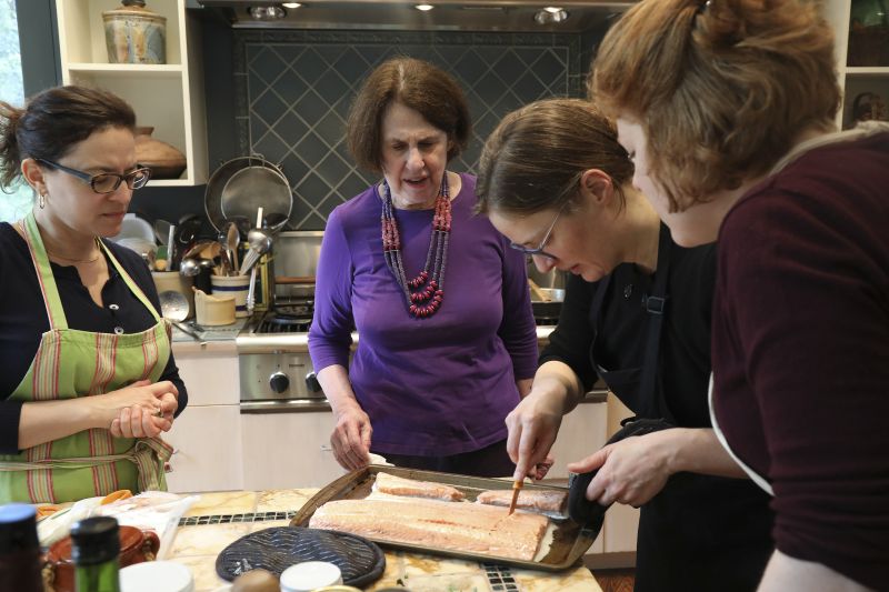 Paula Wolfert, (centre), watches as Emily Kaiser Thelin cuts into baked salmon to check if it needs more time in the oven, at Wolfert's home in Sonoma, California. ― Picture by Jim Wilson/The New York Times