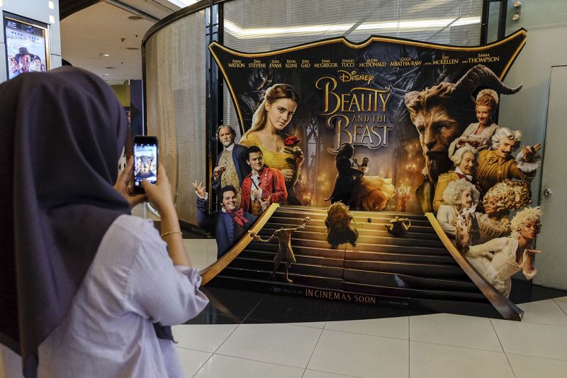 A woman takes a picture of the u00e2u20acu02dcBeauty and the Beastu00e2u20acu2122 poster displayed at a cinema in Kuala Lumpur March 16, 2017. u00e2u20acu2022 Picture by Yusof Mat Isa