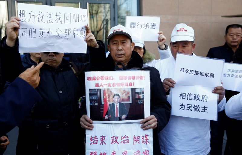 Relatives of passengers aboard Malaysia Airlines flight MH370 hold up placards as they wait to speak to a government official outside the foreign ministry in Beijing March 8, 2017. u00e2u20acu2022 Reuters pic