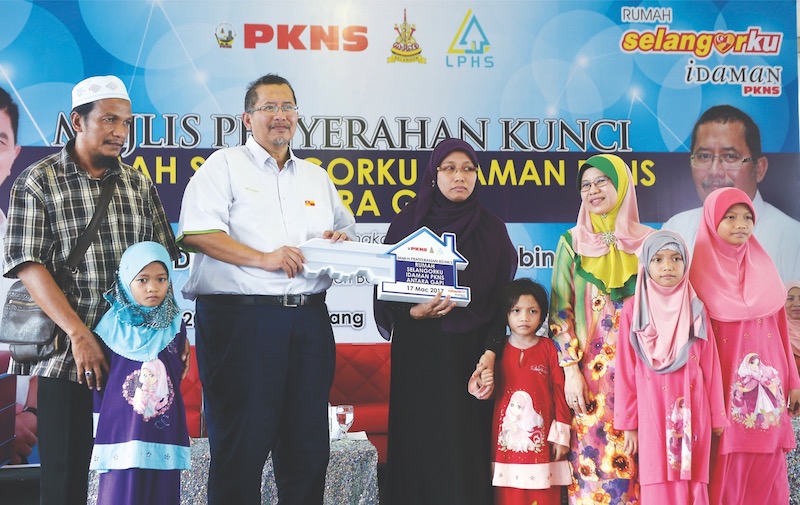 Iskandar presents the mock key to Elizha as husband Mohd Rosli, children Sofiyyah, Najihah, Najjah and Sufina pose together with Noraida. u00e2u20acu201d Bernama pic