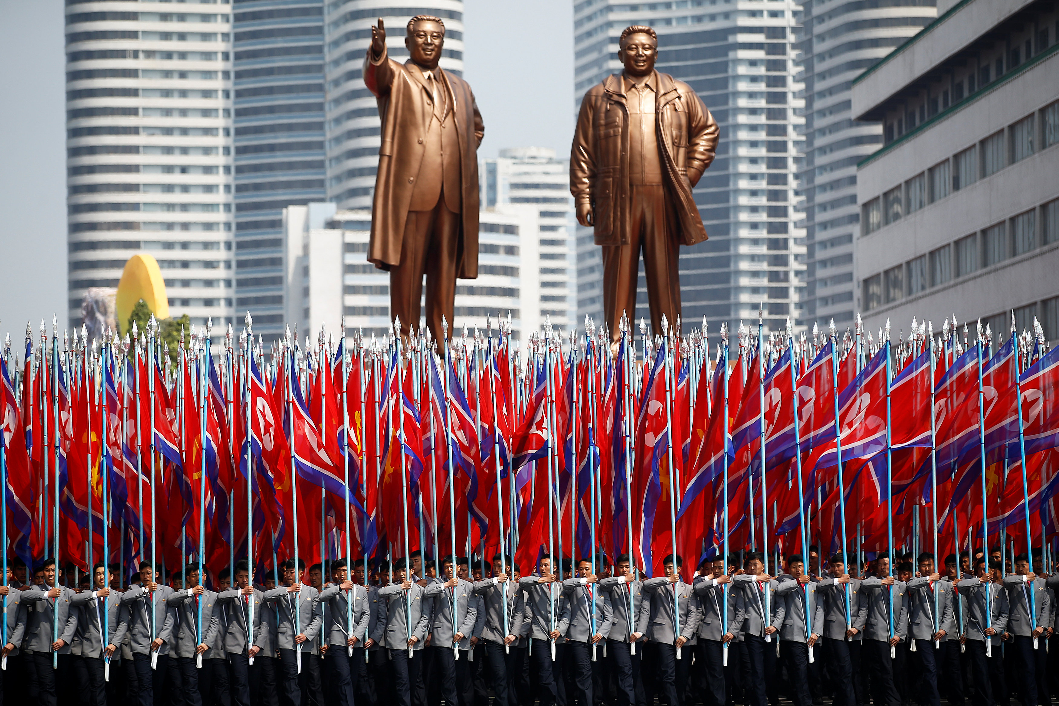 People carry flags in front of statues of North Korea founder Kim Il Sung (L) and late leader Kim Jong Il during a military parade marking the 105th birth anniversary Kim Il Sung in Pyongyang, April 15, 2017. REUTERS/Damir Sagolj TPX IMAGES OF THE DAYn