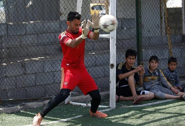 A goalkeeper attempts to stop a shot during a football match in eastern Mosul’s al-Salam neighbourhood on April 7, 2017. 