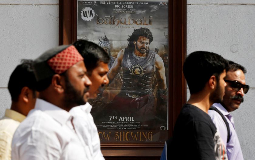 People walk past a poster of an Indian movie u00e2u20acu02dcBaahubali: The Beginningu00e2u20acu2122 outside a movie theatre in New Delhi April 13, 2017. u00e2u20acu201d Reuters pic