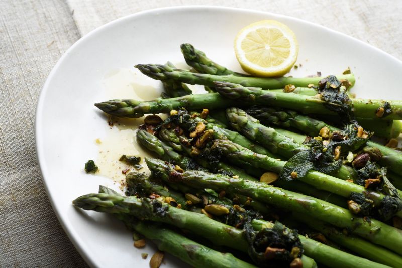 A plate of Steamed medium asparagus with pistachios and brown butter and sage.
