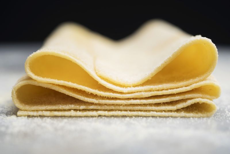 Pasta dough made from scratch, folded into layers and ready to cut by hand into noodles.