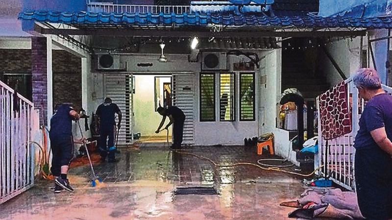 Family members in Taman Bukit Teratai clean their house following the mudflow last week. u00e2u20acu2022 Malay Mail pic