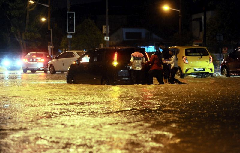 Beberapa orang cuba menolak sebuah kereta yang terperangkap akibat banjir kerana hujan lebat sejak petang tadi semasa tinjauan di sekitar Bayan Baru malam tadi. u00e2u20acu201d Foto Bernamann