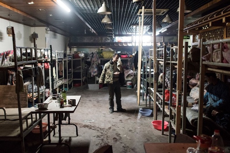 A man gets dressed in a dormitory, where 60 workers live, in a hutong in Beijing March 22, 2017. — AFP pic