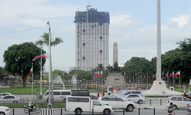 The 49-storey Torre de Manila high-rise condominium looms in the background from the Jose Rizal tomb and monument at Luneta Park in Manila. u00e2u20acu201d AFP pic