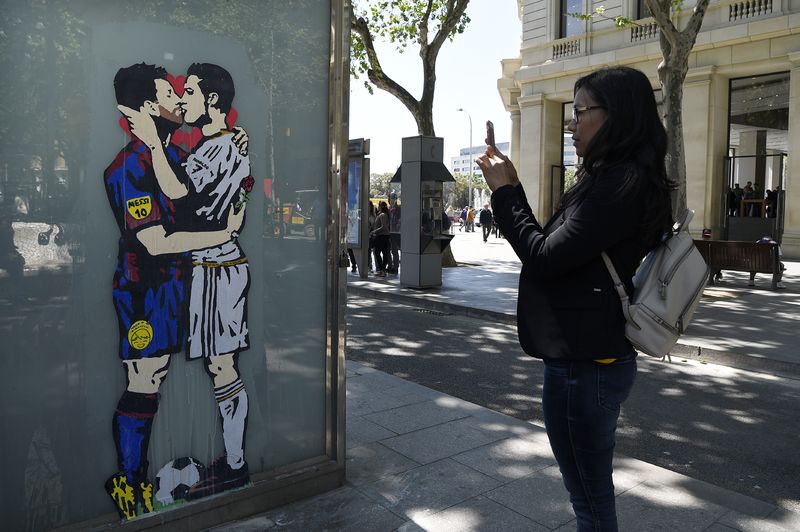A woman takes a picture of the street art on April 21, 2017 in Barcelona, that shows Barcelonau00e2u20acu2122s Lionel Messi and Real Madridu00e2u20acu2122s Cristiano Ronaldo kissing each other two days before the El Clasicou00e2u20acu2122 match between Real Madrid and FC Barcelona. u00e2u20acu201d AFP 