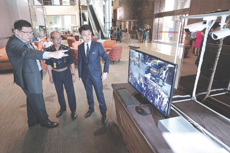 Wan (left) shows the quality of the surveillance cameras to Bukit Aman Community Safety and Crime Prevention Department principal assistant director Senior Asst Commissioner Datuk Zainal Abu (centre) and Chong at Sime Darby Convention Centre. u00e2u20acu201d Picture 