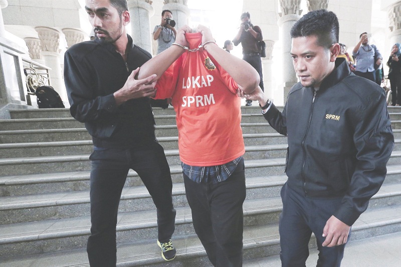 Shaikh Abdul Adzis being led out of the Putrajaya Court Complex yesterday. u00e2u20acu201d Picture by Azinuddin Ghazali