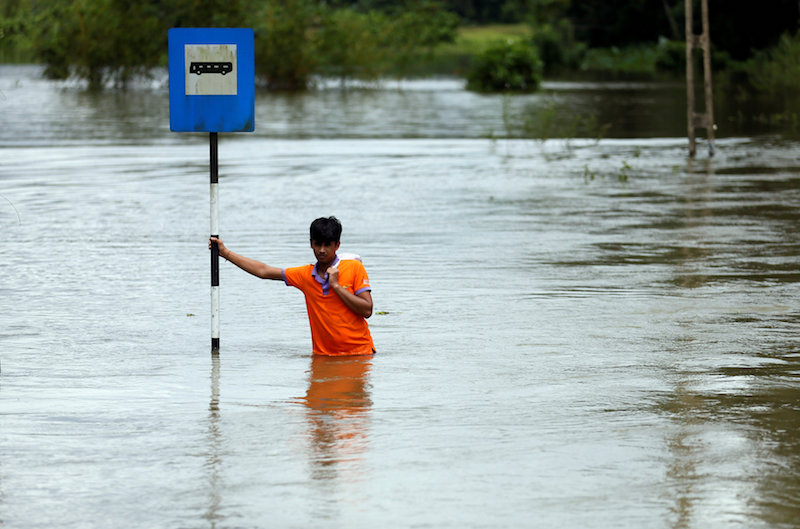 A man holds a bus stop post on a flooded road as he waits for a military vehicle to go to a town, in Bulathsinhala village, in Kalutara,u00c2u00a0Sriu00c2u00a0Lankau00c2u00a0May 27, 2017.u00c2u00a0u00e2u20acu201d Reuters pic