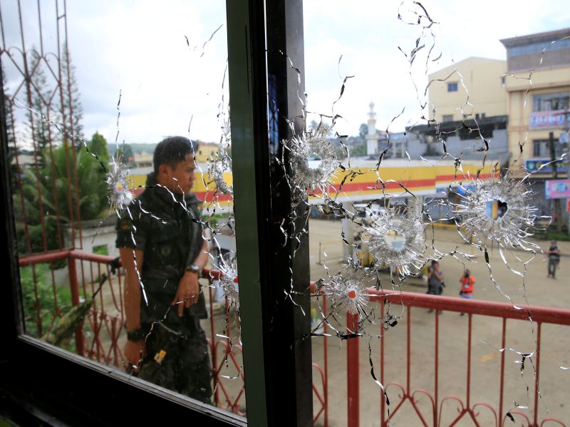 A policeman stands on guard behind a window full of bullet holes as government soldiers assault the Maute group in Marawi City, Philippines May 31, 2017. u00e2u20acu201d Reuters pic