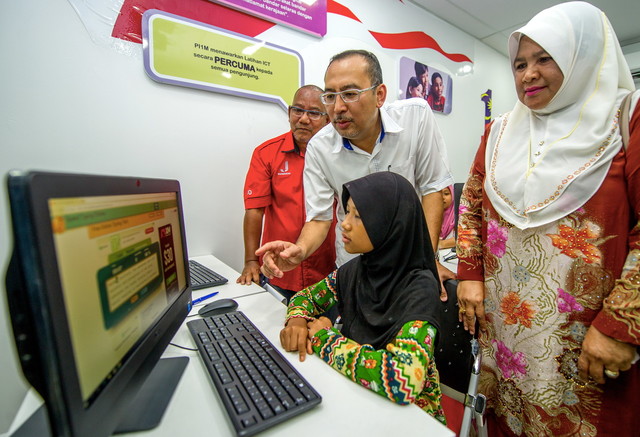 Timbalan Menteri Komunikasi dan Multimedia Datuk Jailani Johari (berdiri,tengah) membantu seorang murid kemudahan internet pada merasmikan Pusat Internet 1Malaysia Kampung Kalai hari ini. -- Foto Bernamann