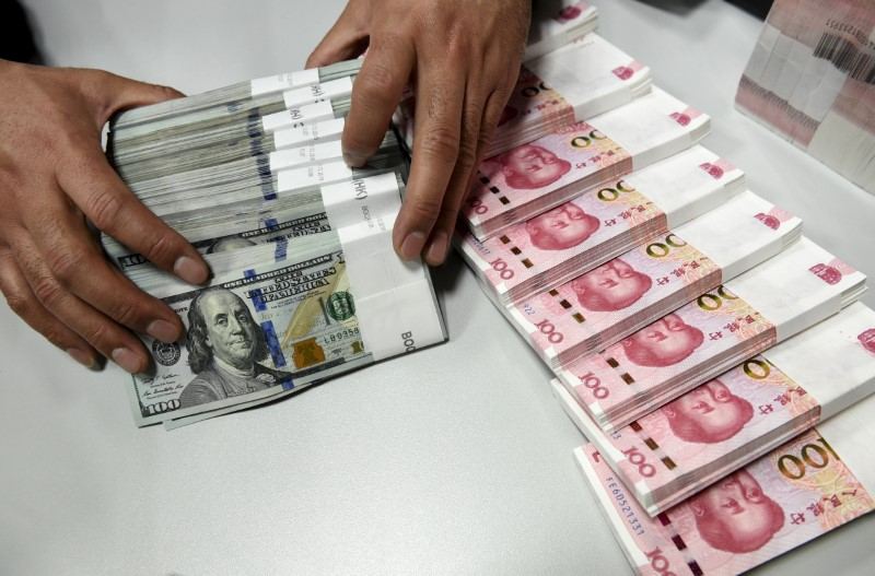 A clerk counts Chinese yuan and US dollar banknotes at a branch of Bank of China in Taiyuan, Shanxi province, January 4, 2016. u00e2u20acu201d Reuters pic