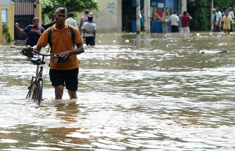 Sri Lankan residents walk through floodwaters in Dodangoda village in Kalutara on May 28, 2017. u00e2u20acu201d AFP pic 