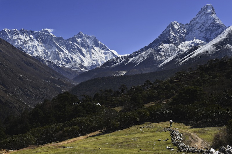 In this photograph taken on April 20, 2015, a Nepalese porter carries goods along a pathway in the Himalayas, with Mount Everest on the left, in the village of Tembuche in the Khumbu region of northeastern Nepal. u00e2u20acu201d AFP pic