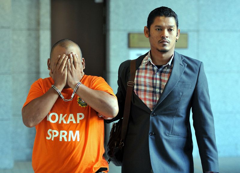 A MACC officer escorting a suspect to obtain a remand order on a case gambling houses and massage centres in Melaka at the Magistratesu00e2u20acu2122 Court in Putrajaya, May 19, 2017. u00e2u20acu201d Bernama pic