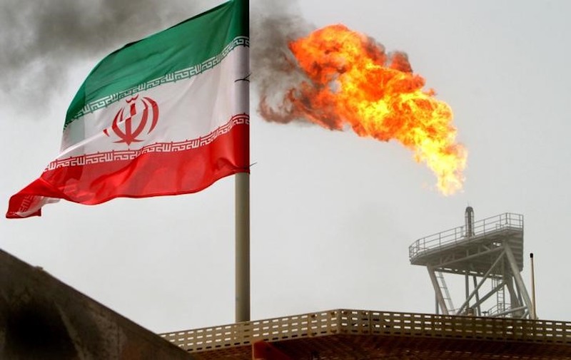 A gas flare on an oil production platform in the Soroush oil fields is seen alongside an Iranian flag in the Persian Gulf, Iran, July 25, 2005. u00e2u20acu201d Reuters pic