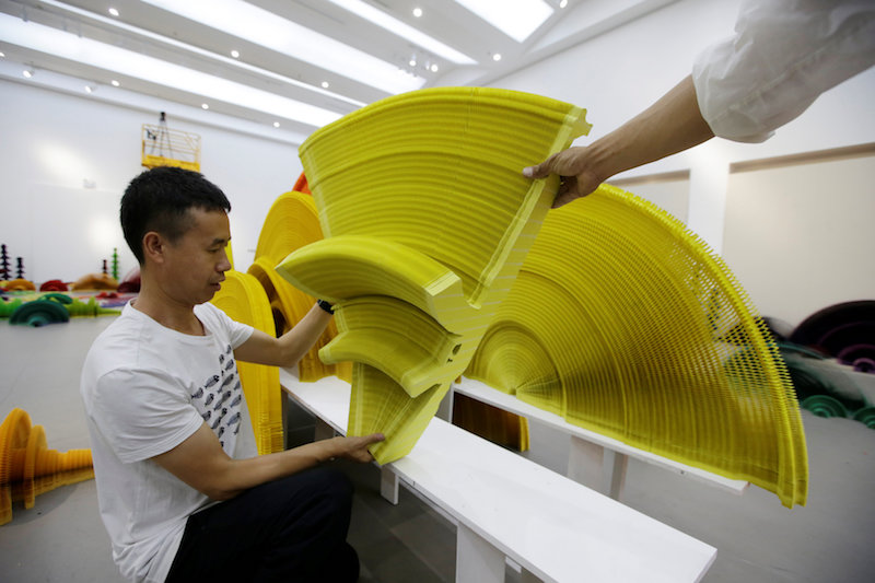 Chinese artist Li Hongbo and his assistant set up a paper sculpture in the shape of an AK 47 assault rifle for his work ‘Ocean of Flowers’ at Eight One Art Museum in Beijing June 13, 2017. — Reuters pic