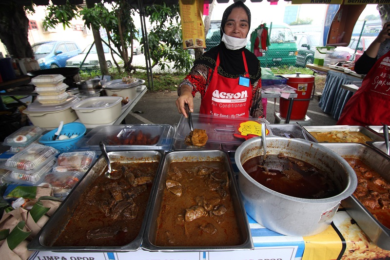 Stall operator Normah Yakun dishes out Opor, a traditional meat dish originating from Pahang, at a Ramadan bazaar in Kuantan June 8, 2017. u00e2u20acu201d Bernama pic