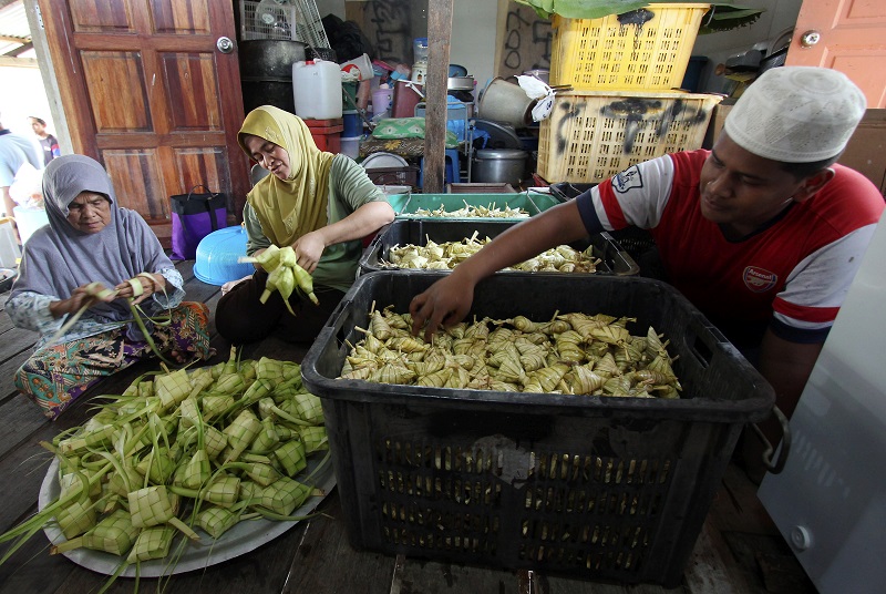 Halimah Kadir,73 (kiri) bersama anak saudaranya Rokiah Mat Ali,43 (dua, kiri) dan cucu Mohd Nabil Ghazali, 15, sibuk menyiapkan ketupat nasi dan pulut di rumahnya di Kampung Ubai, Kuantan 23 Jun, 2017. u00e2u20acu201d Foto Bernama