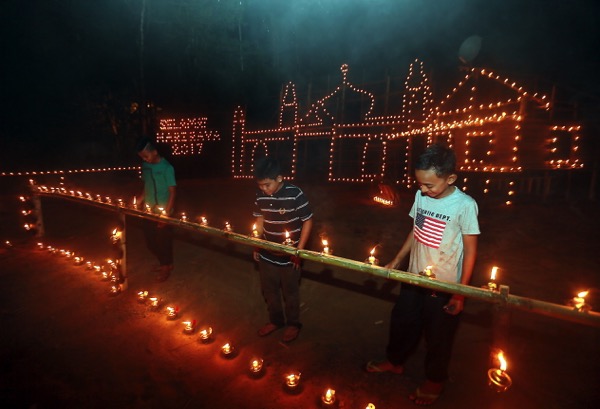 (From left) Mohd Farihin Azrin, Mohd Nor Hakim Md Ruzanil and Mohd Ashraf Azmi light noil lamps in front of the entry by Kampung Keroh Hulu. u00e2u20acu201d Picture by Farhan Najibn