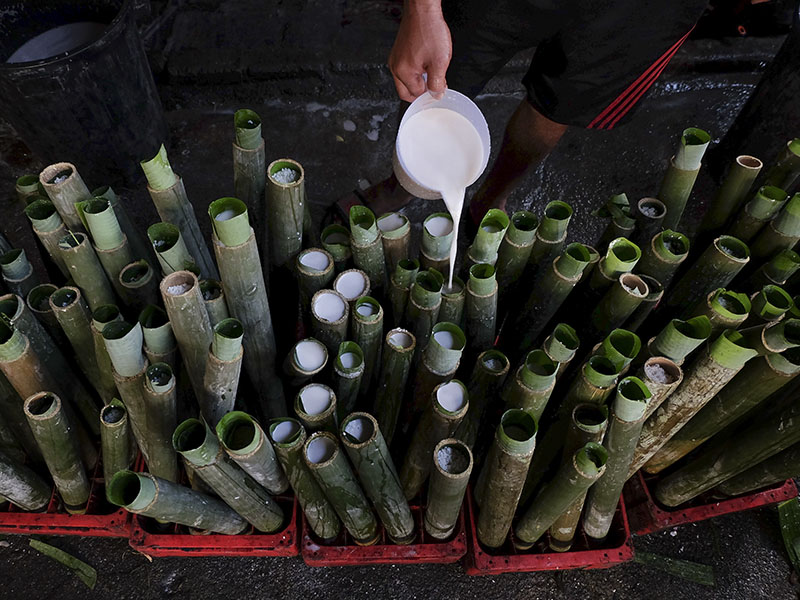 A man pours coconut milk into bamboos filled with glutinous rice as he prepares a Malay traditional dish called ‘lemang’. — Picture by Yusof Mat Isa