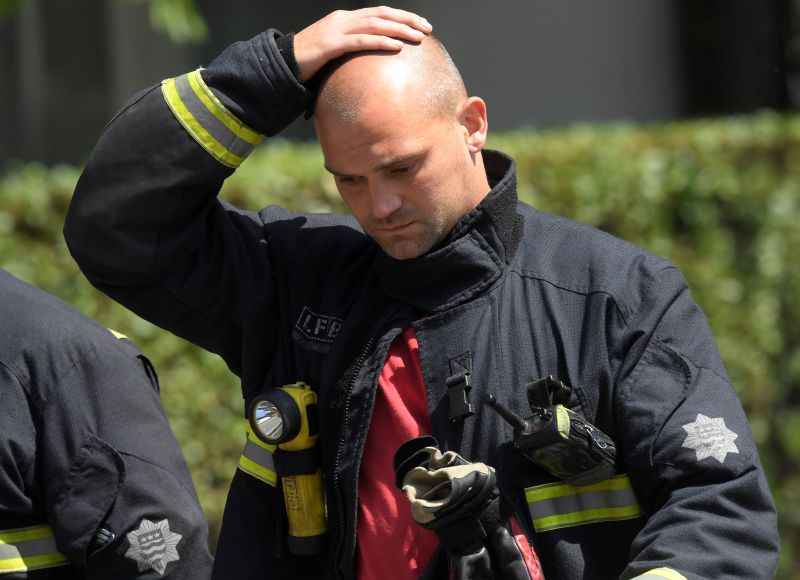 Firefighters rest near a tower block, severely damaged in a serious fire, in north Kensington, West London June 14, 2017.u00e2u20acu201d Reuters pic