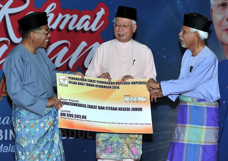 Prime Minister Datuk Seri Najib Razak witnessed the handing over of zakat distribution from cooperatives by Felda Felda chairman Tan Sri Shahrir Samad (right) with Johor Menteri Besar Datuk Seri Mohamed Khaled Nordin (left) at FELDA Sungai Sayong, Kulai, 
