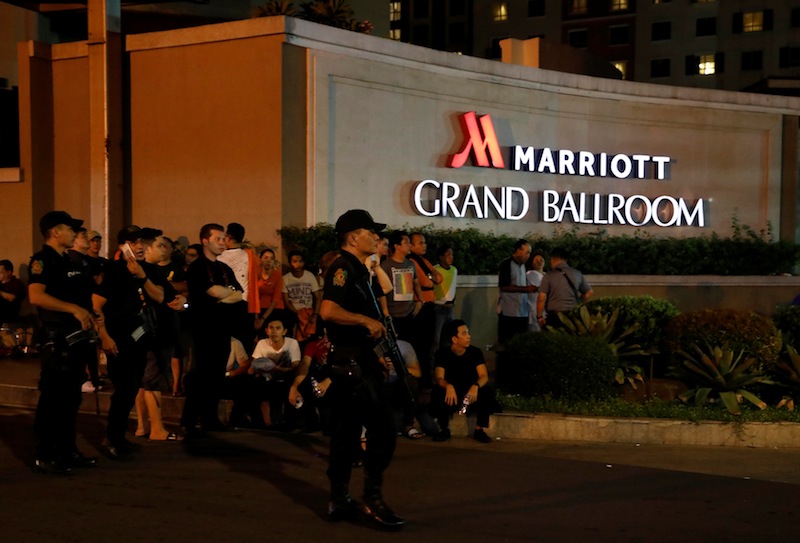 Policemen stand guard near evacuated employees of a hotel near a situation at a Resorts World building, in Pasay City, Metro Manila, Philippines June 2, 2017. u00e2u20acu201d Reuters pic