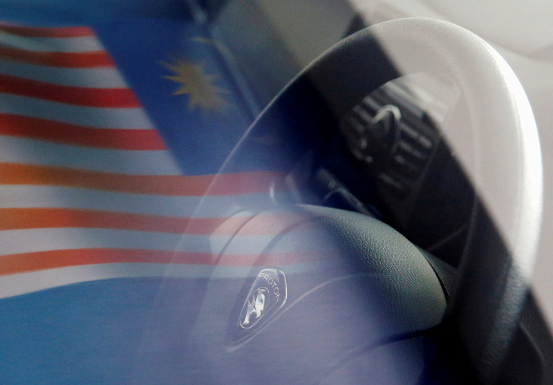 A Malaysian flag is reflected on a car window at a Proton showroom in Puchong October 3, 2016. u00e2u20acu201d Reuters pic