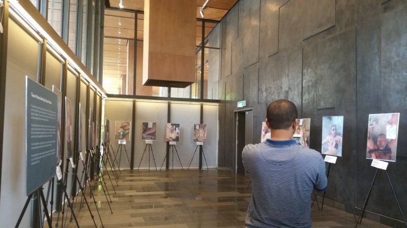 A visitor takes photos at the exhibition of a select 19 out of 55,000 smuggled photos of Syrians allegedly starved and tortured to death by their own government.