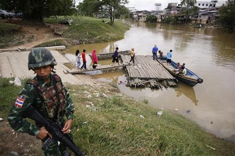 A soldier stands guard on the Thai side of the river as people prepare to cross into Malaysia in Sungai Kolok in southern Narathiwat province March 8, 2013. REUTERS