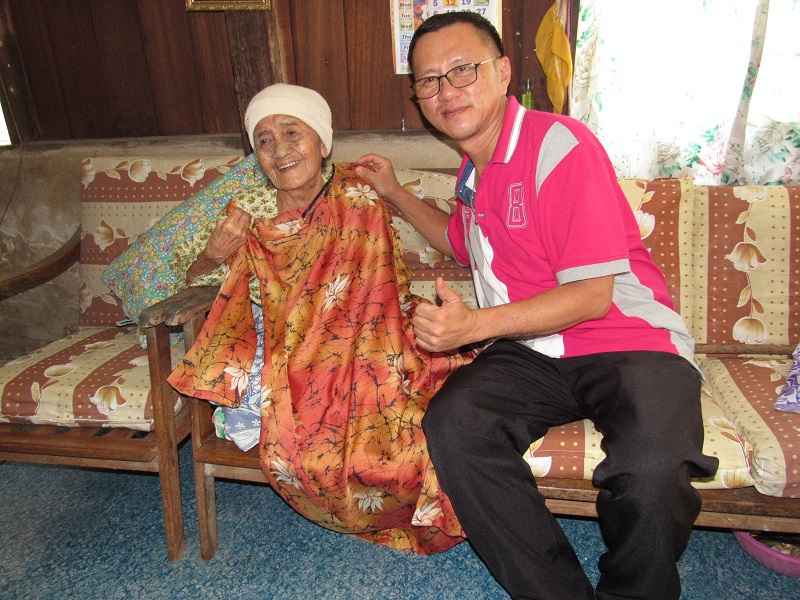 Nenek Siti Zahrah Wahab, 102, tersenyum gembira setelah Tan Khim Peng, 53, membantu warga emas itu memakai baju kurung baharu menyambut Aidilfitri di Kampung Tanjung Belit, Kulim 24 Jun 2017. u00e2u20acu201d Foto Bernama