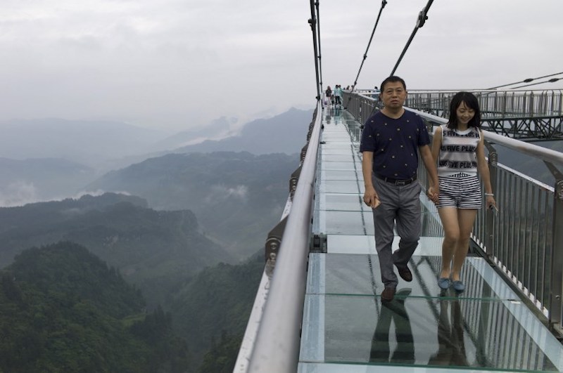 A couple walks on a glass-bottomed skywalk, certified as the worldu00e2u20acu2122s longest, at the Ordovician park in Wansheng June 1, 2017. u00e2u20acu201d AFP pic