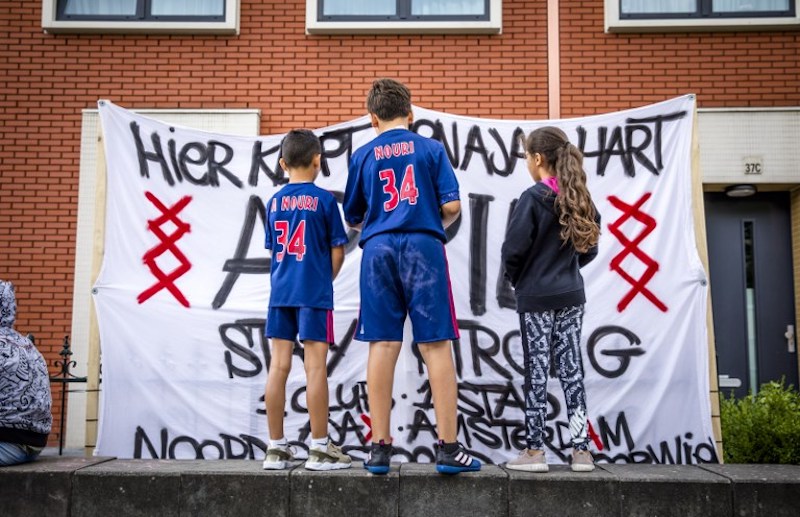 Fans wearing shirts with the number 34 of Ajax midfielder Abdelhak Nouri stand in front of a banner reading u00e2u20acu02dcHere beats a Ajax heart u00e2u20acu201d Stay Strong Appieu00e2u20acu2122 at the playeru00e2u20acu2122s home in Amsterdam July 13, 2017. u00e2u20acu201d AFP pic