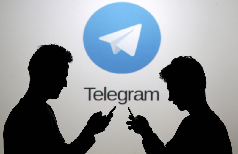 Men pose with smartphones in front of a screen showing the Telegram logo in this picture illustration November 18, 2015. u00e2u20acu201d Reuters pic